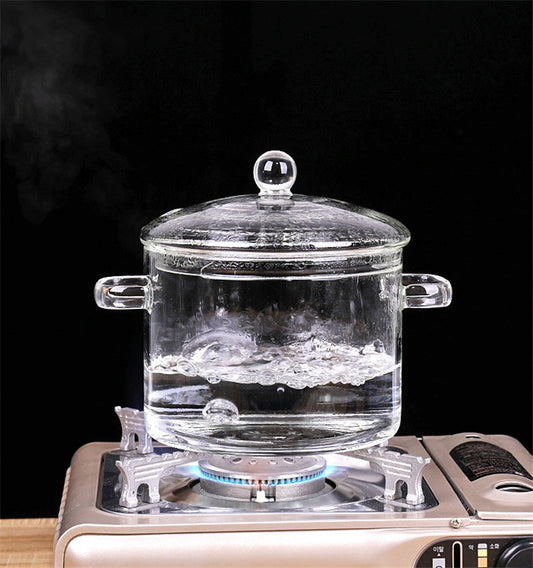 Transparent glass pot boiling water on a stove.